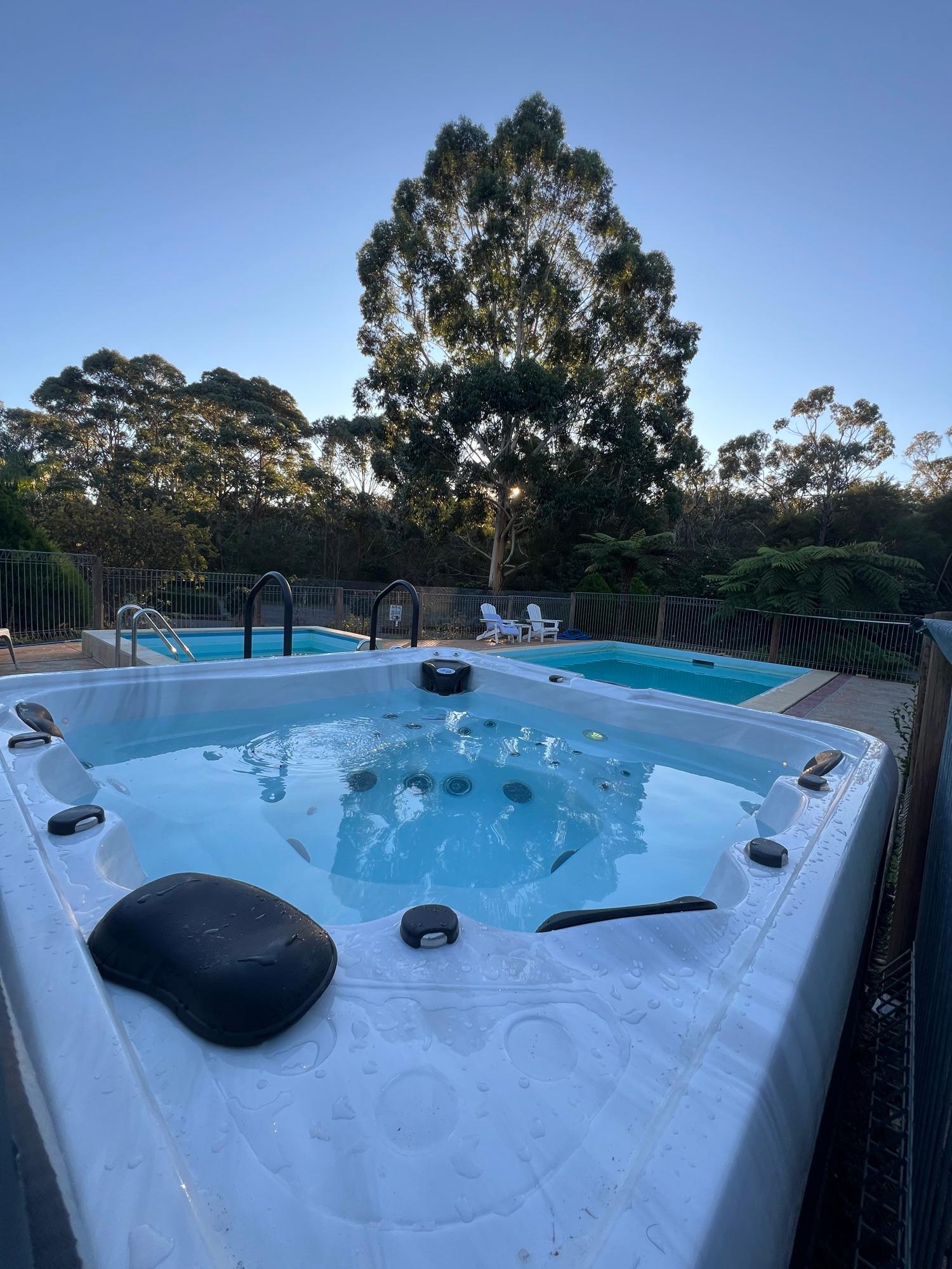 Outdoor spa beside the swimming pools at dusk, framed by Yarra Valley bushland at Sanctuary House