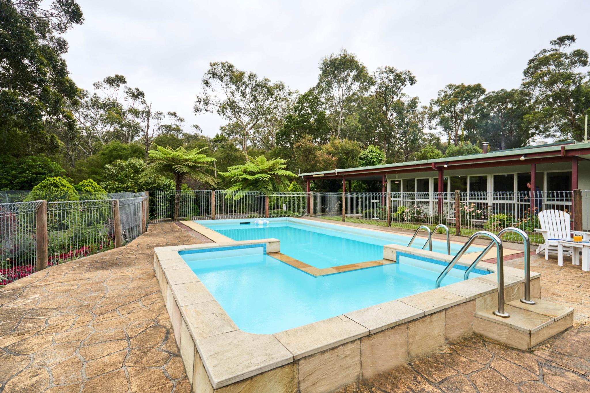 Outdoor swimming pool surrounded by gardens at Sanctuary House Healesville