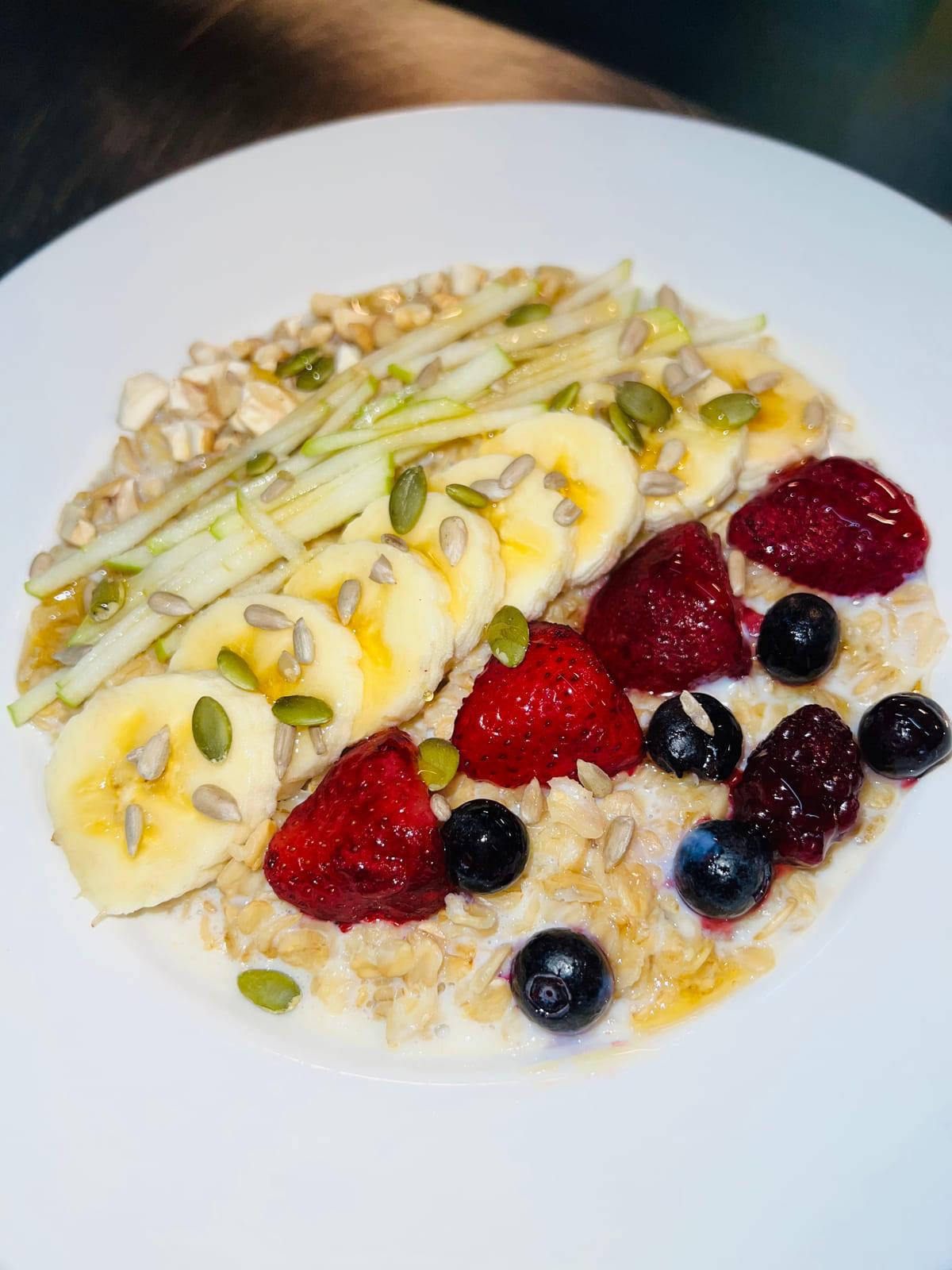 Oat Porridge — creamy oats topped with banana, strawberries, blueberries, apple and seeds