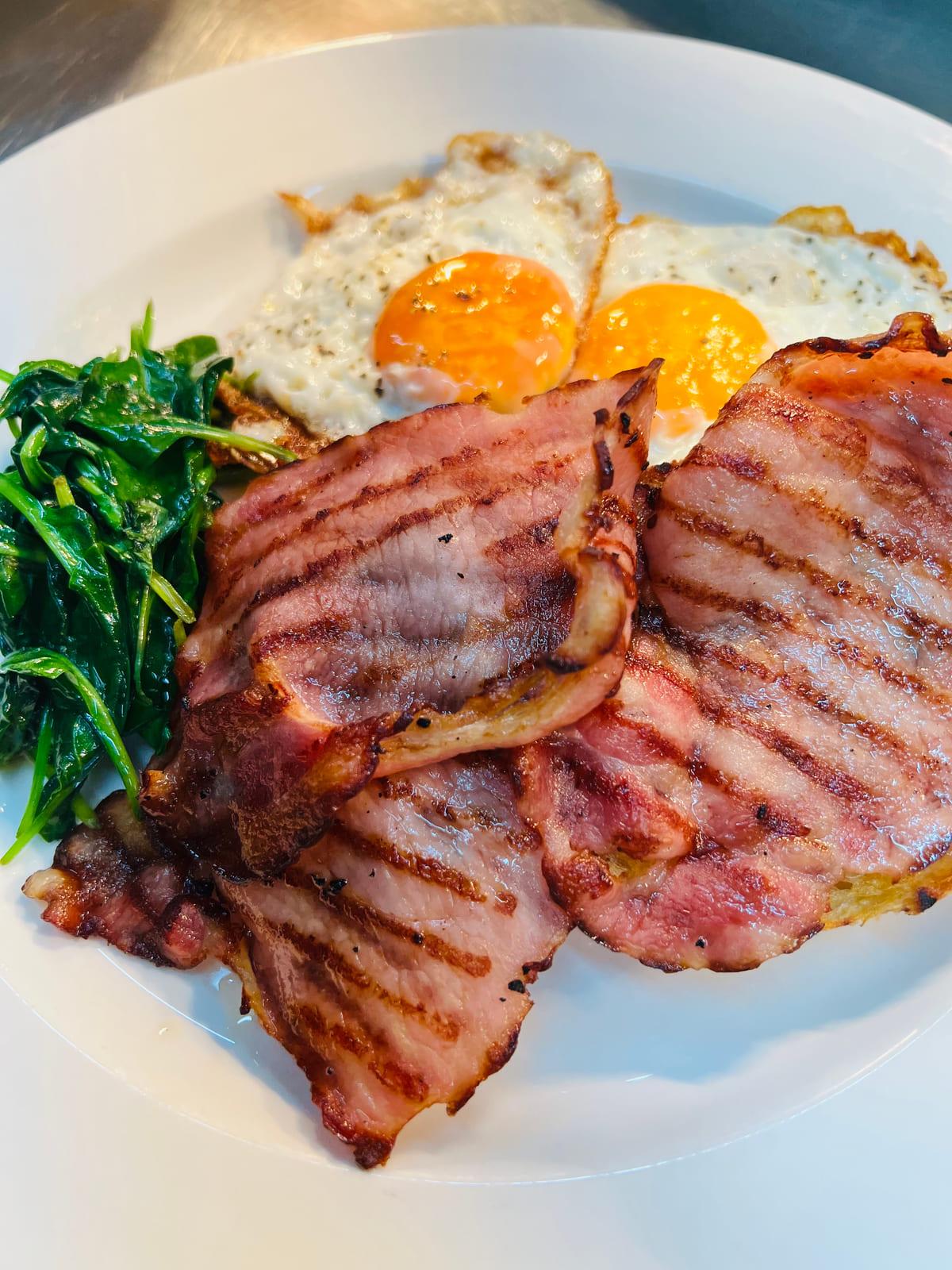 Eggs Your Way — fried eggs on sourdough with grilled bacon and wilted spinach