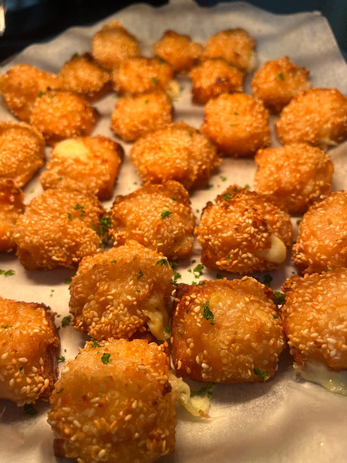 Golden sesame-crumbed cheese bites scattered with parsley, served as function canapés