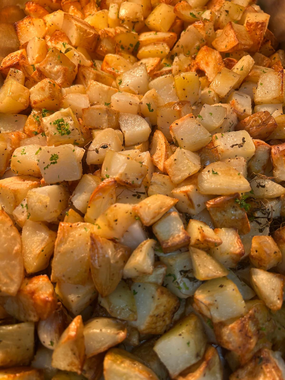 Tray of golden roast potatoes tossed with herbs and thyme for a function buffet