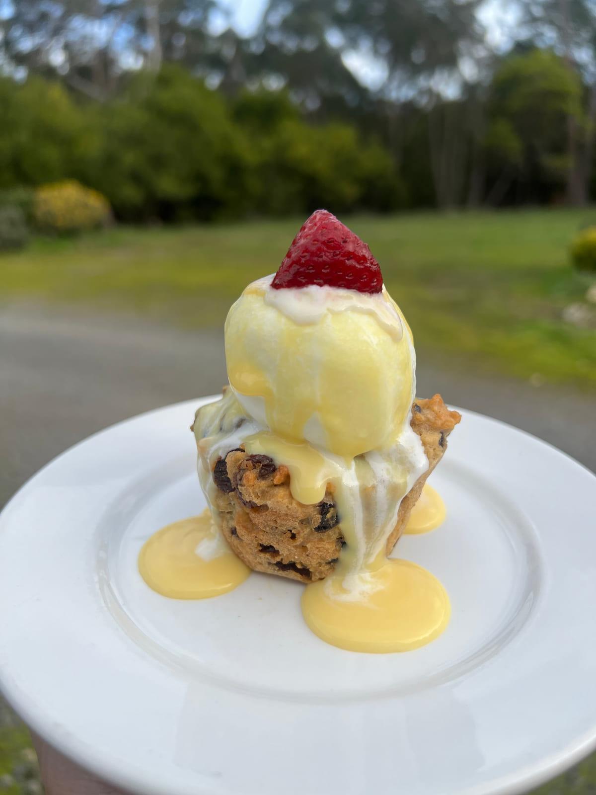 Warm fruit pudding served with vanilla ice cream, pouring custard and a strawberry
